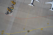 View from above airplanes and luggage carts on airport tarmac