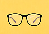 Large eyeglasses with cracked lens on yellow background