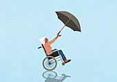 Senior woman in wheelchair holding umbrella blowing in wind on blue background