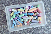 View from above multicolored sidewalk chalk in plastic bin