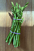 Still life view from above vibrant green asparagus bunch on wooden background