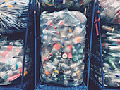 View from above plastic bottles wrapped in recycling bags in bins at recycling center