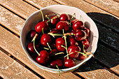 Still life close up vibrant red cherries in bowl on sunny table