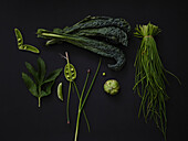 Still life flat lay variety of green vegetables on black background