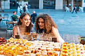 Transsexual woman and girlfriend enjoying pastries in a cafe