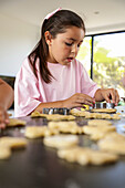 Young girl baking biscuits in a sunny kitchen
