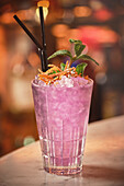 Pink cocktail with ice cubes in glass on counter