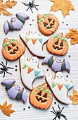 Multicolored Halloween homemade cookies on white wooden background.