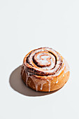 Fresh cinnamon roll with creamy icing on a white background