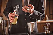 Bartender pouring alcohol from a jigger into a cocktail shaker