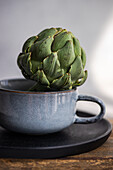 Fresh artichoke in a stylish ceramic cup