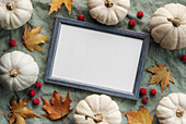 Autumnal composition. Photo frame, pumpkins, dried leaves on greenery