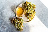 Top view of white wine and grapes on a sunlit table