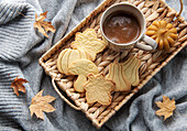 Cup of coffee, cookies on tray, yellow leaves.