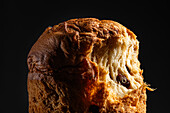 Close-up of a freshly baked, fruit-filled panettone against a dark background