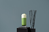 Matcha tea latte with whipped cream on a modern background
