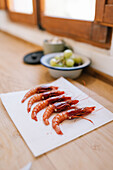 Fresh prawns on a chopping board with blurred crockery in the background