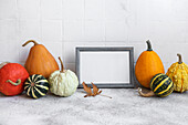 Picture frame and pumpkin decor on the table over white tile bac