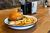 Juicy burger with crispy chips on white plate in a restaurant