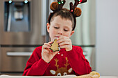 Junge mit Rentiergeweih bereitet Weihnachtsplätzchen zu