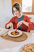 Frau, die zu Hause lächelnd eine Mahlzeit mit Meeresfrüchten genießt