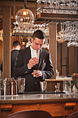 Bartender pours syrup into a jigger while preparing a cocktail