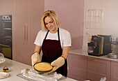 Frau lächelt beim Backen eines Kuchens in einer modernen Küche