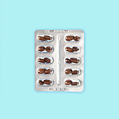 Blister pack of coffee bean shaped pills on a light blue background, implying a concept of energy or caffeine supplements