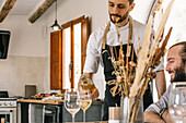 Private chef serving wine to a man at a kitchen party