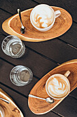Cappuccino and glasses of water from above on a wooden table