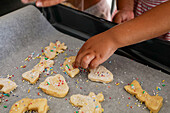 A child decorates biscuits with colourful sprinkles