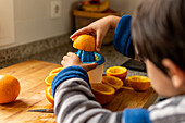 Child preparing fresh orange juice in a cosy kitchen