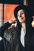 Stylish Caucasian woman adjusts her hat in a lively setting