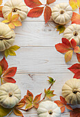 Herbstblätter und Kürbisse vor altem Holzhintergrund