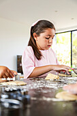 Young girl carefully baking biscuits in a sunny kitchen
