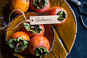 Elegant ausgestellte Kakis in einem herbstlichen Arrangement