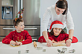 Mutter und Zwillinge backen in der Küche Weihnachtsplätzchen