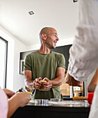Man smiles while baking biscuits with family in the kitchen