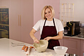 Blonde woman prepares dough in a modern kitchen