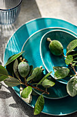 Fresh feijoas with leaves on a turquoise plate, top perspective