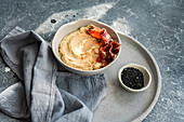 Top view of hummus with jamón and black sesame seeds