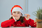 Little girl in Christmas clothes holding a Christmas cookie cutter