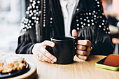 Woman enjoying coffee in a café with smartphone on the table