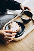 Woman enjoying coffee and croissant at a wooden table in a cafe