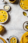 Rustic pumpkin soup with feta and seeds on a grey background