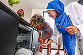 Friends load the dishwasher together in a kitchen