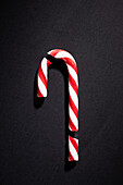 Single candy cane on a dark background, top view