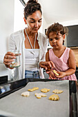 Mother and daughter baking biscuits together in the kitchen
