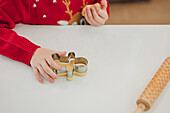 A festively dressed child bakes Christmas biscuits