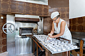 Baker preparing pastries next to an industrial oven in a bakery